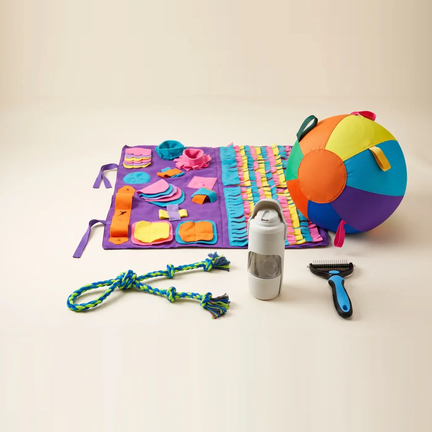 The Full Kit: a purple snuffle mat, a rainbow herding ball, a blue rope tug, a grey travel bottle and a blue undercoat rake